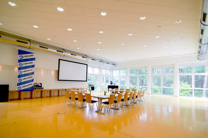 Der gelbe Saal mit großem Konferenztisch, Fahne und Leinwand