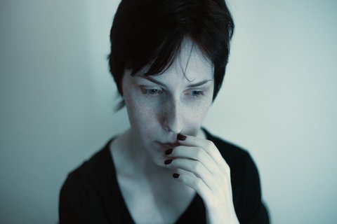Portrait einer nachdenklichen Frau in dunklen Blautönen